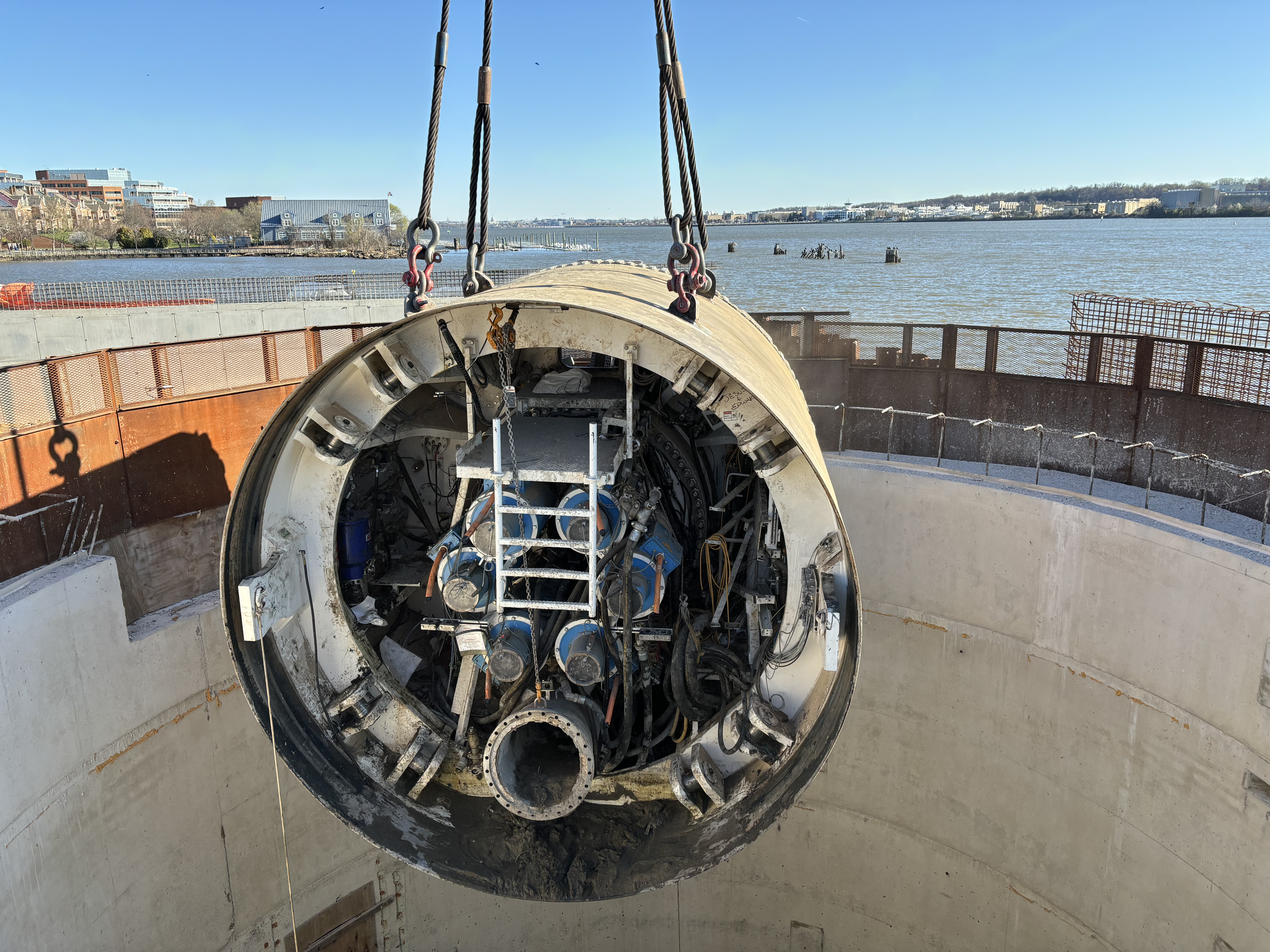 The cutterhead of Hazel the Tunnel Boring Machine is hoisted out of the shaft beside the Potomac River